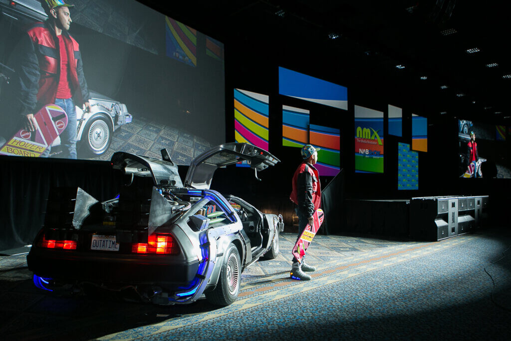 Photo of Pat Flynn on stage dressed as Marty McFly standing next to a Delorean