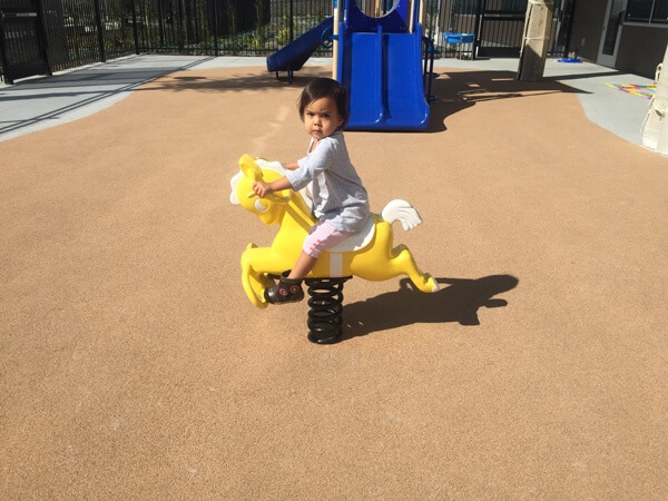 Pat's little daughter playing at the park on a horsey mounted on a giant spring.