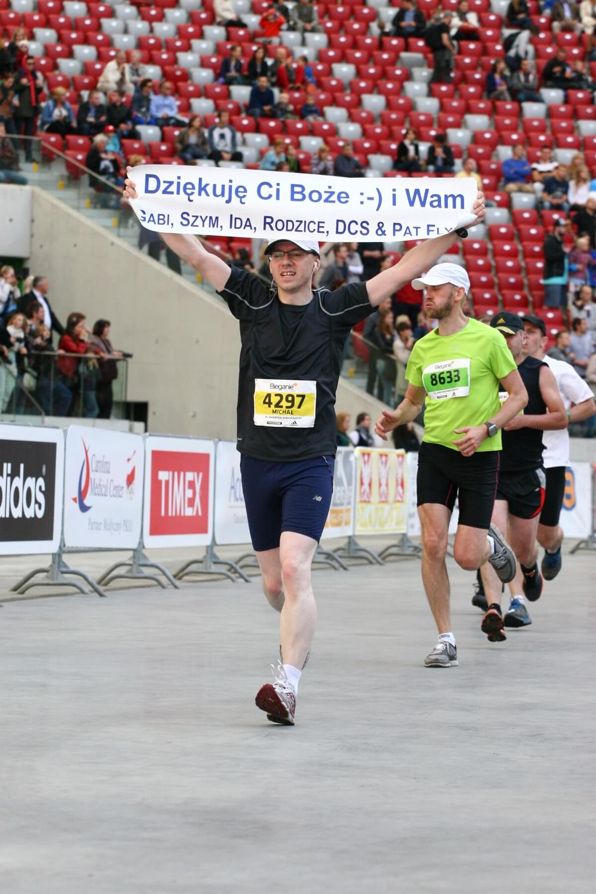 Picture of guy running and holding a sign in Polish. One of the six names listed on the sign is Pat Flynn.