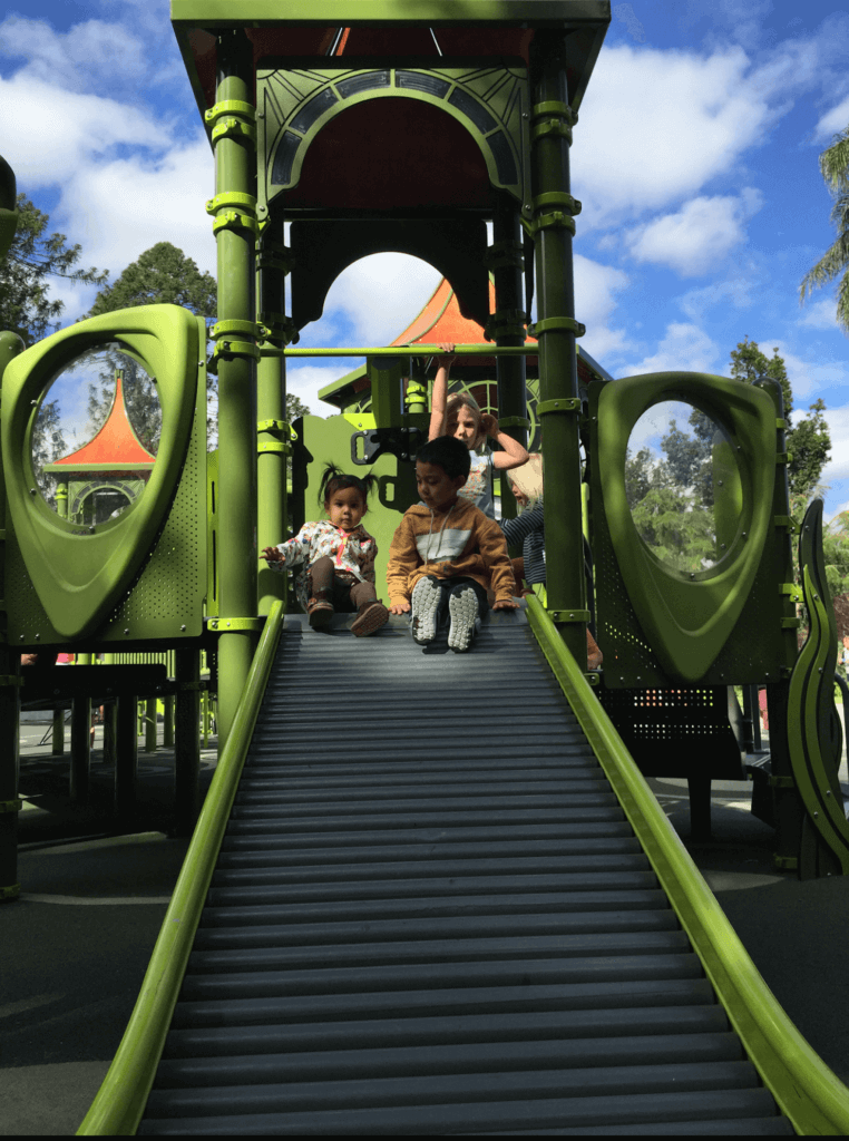 Photo of Pat's two young kids sitting on a green slide.