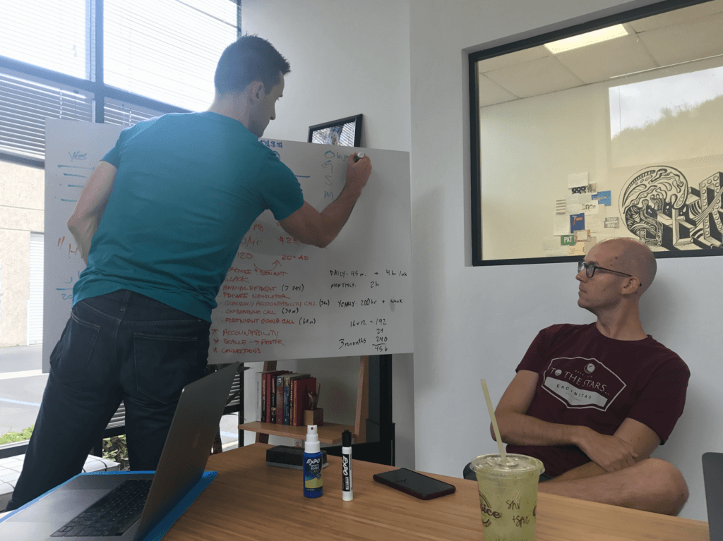 Photograph of Matt Gartland and Caleb, working out details on a white board.